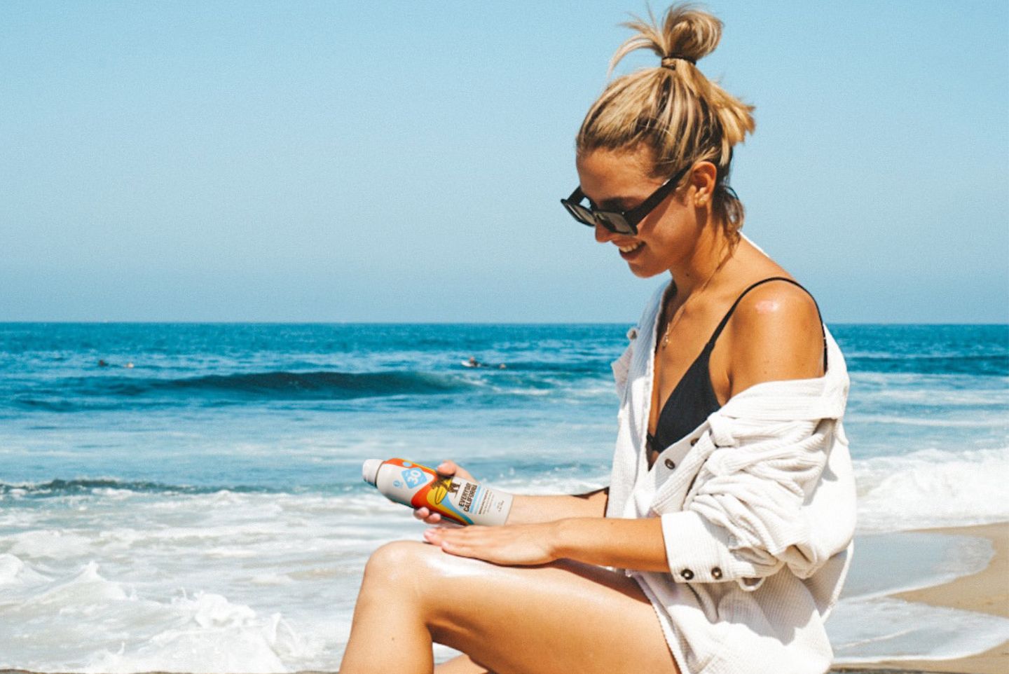 A girl on the beach holding Everyday California's Reed Safe Sunscreen mineral based