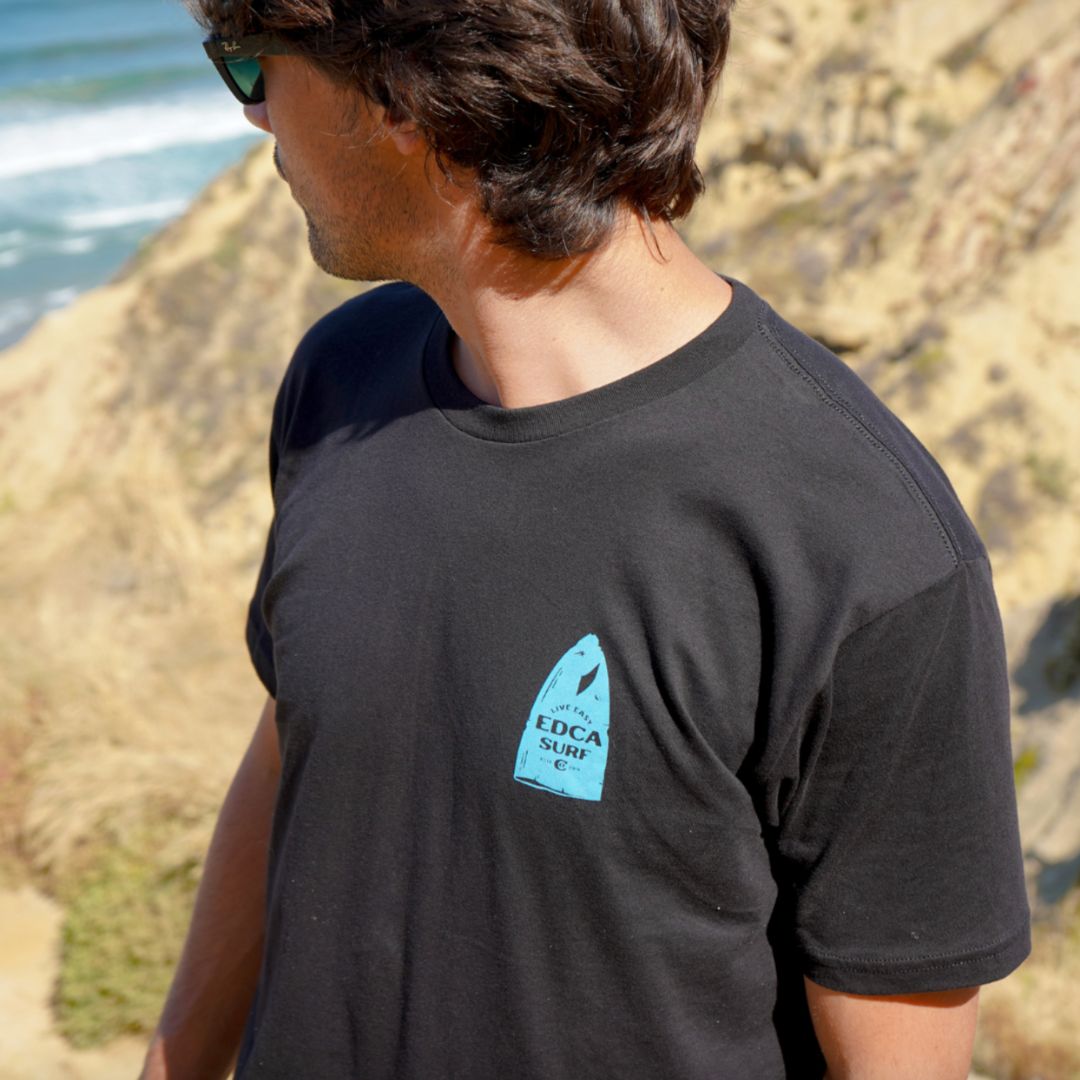 A California man wearing the beater board tee from everyday California looking out on Torrey Pines trail onto the ocean 