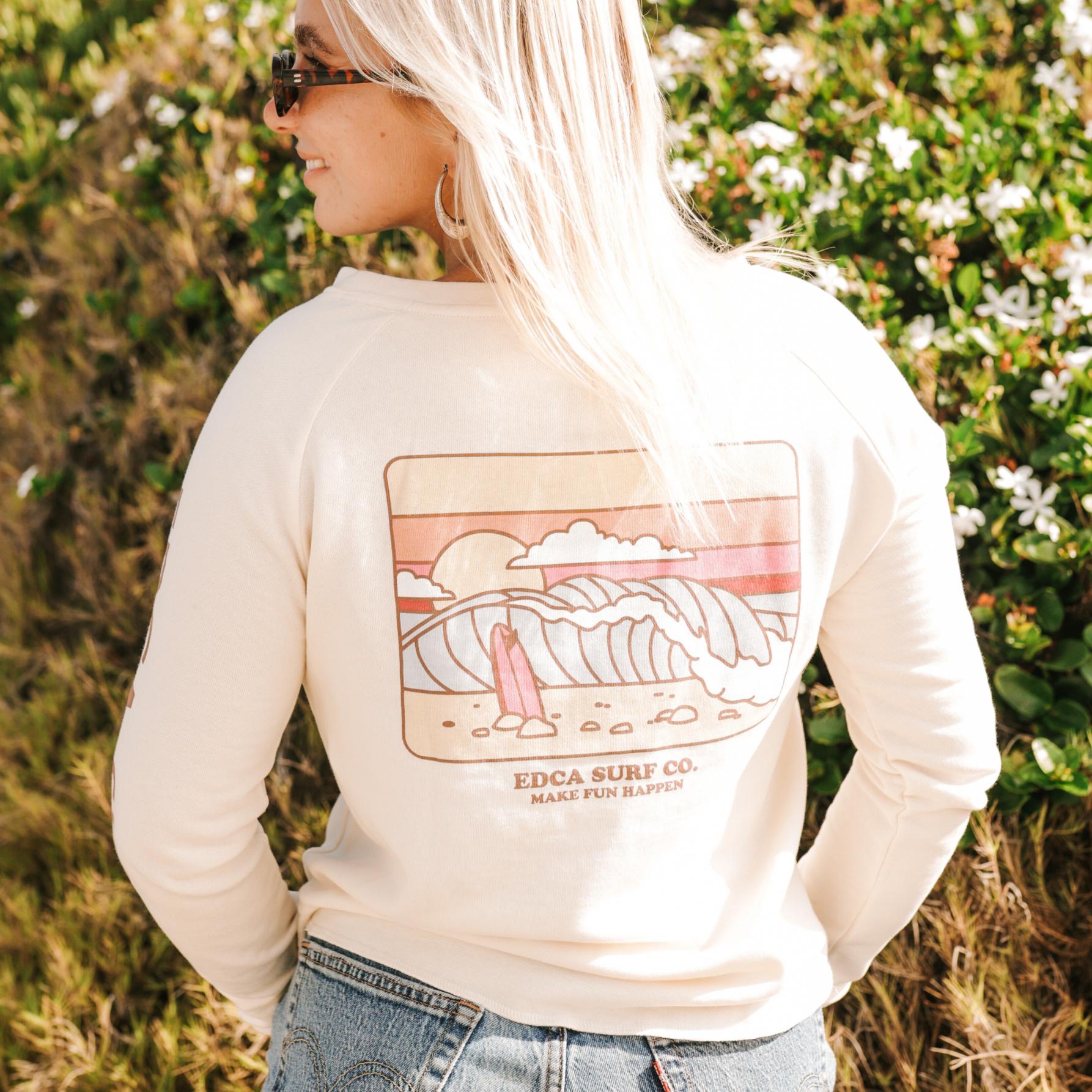 Woman wearing a cream long-sleeve shirt with a graphic design outdoors.