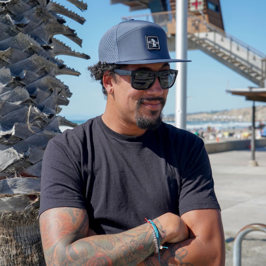 The Cormorant Hat on the beach by the lifeguard tower with a California guy smiling