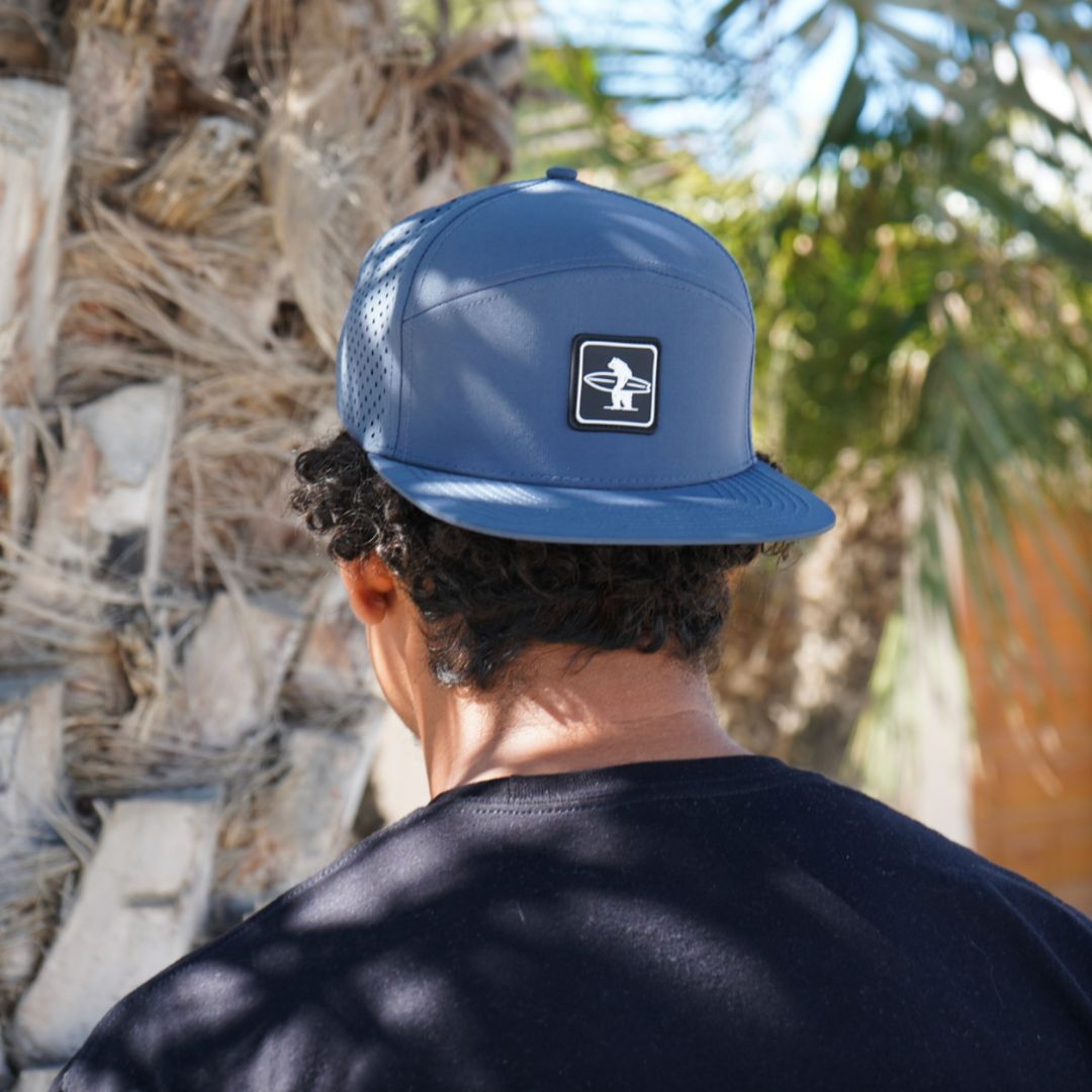The navy cormorant hat underneath a tree with some shadows on a sunny day in California