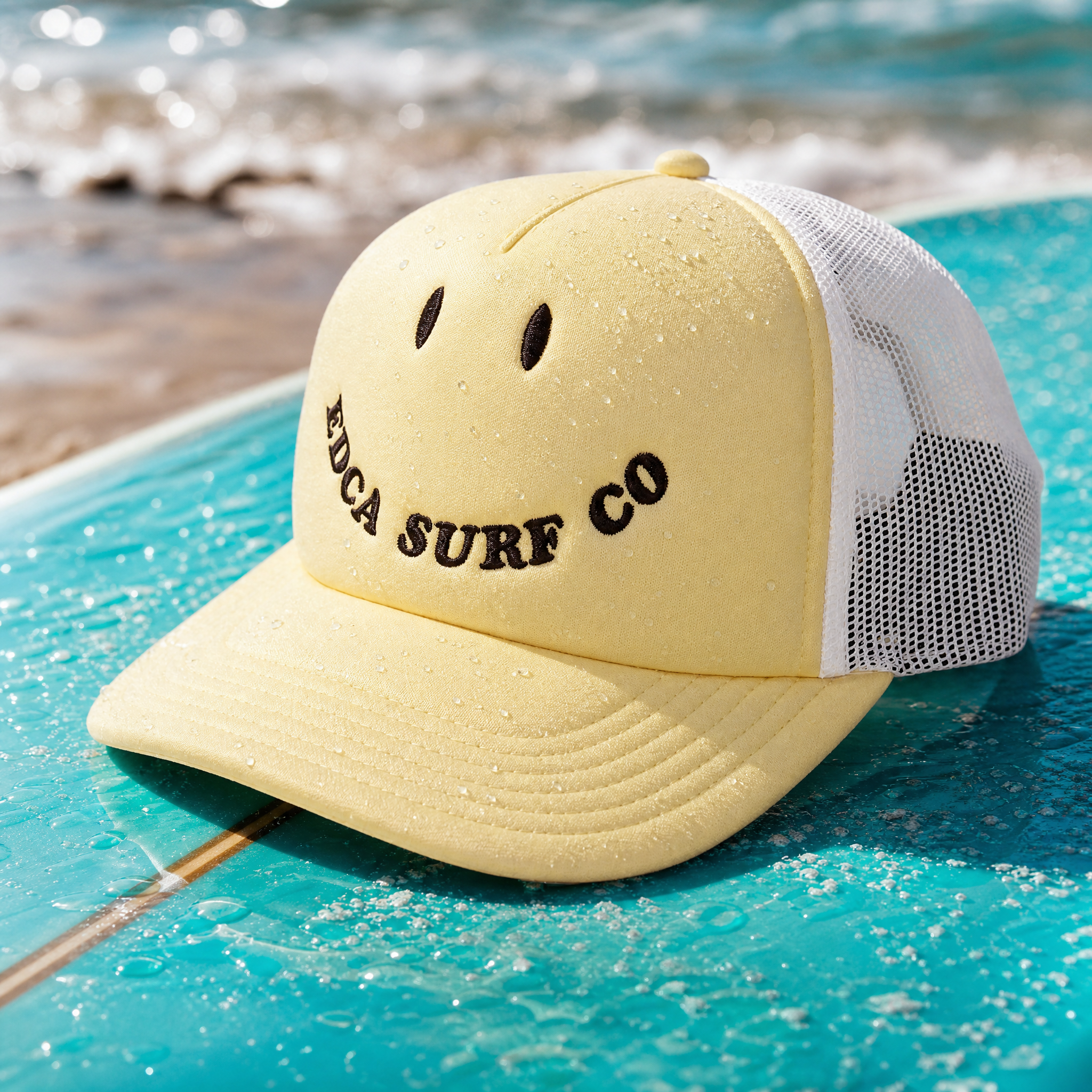 Yellow foam trucker snapback hat sitting on top of a bright blue waxed surfboard.
