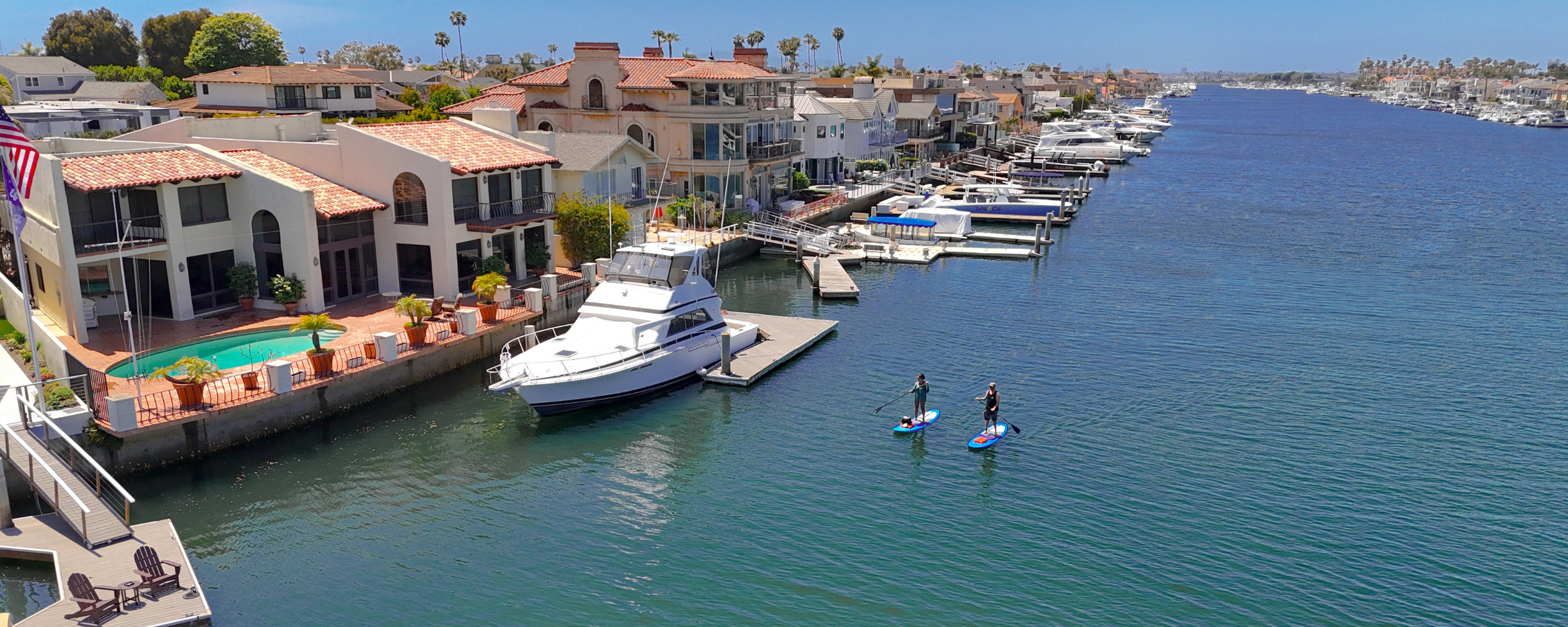 Two stand up paddle boarders paddling through Huntington Harbour on an Everyday California Stand Up Paddle Board rental.