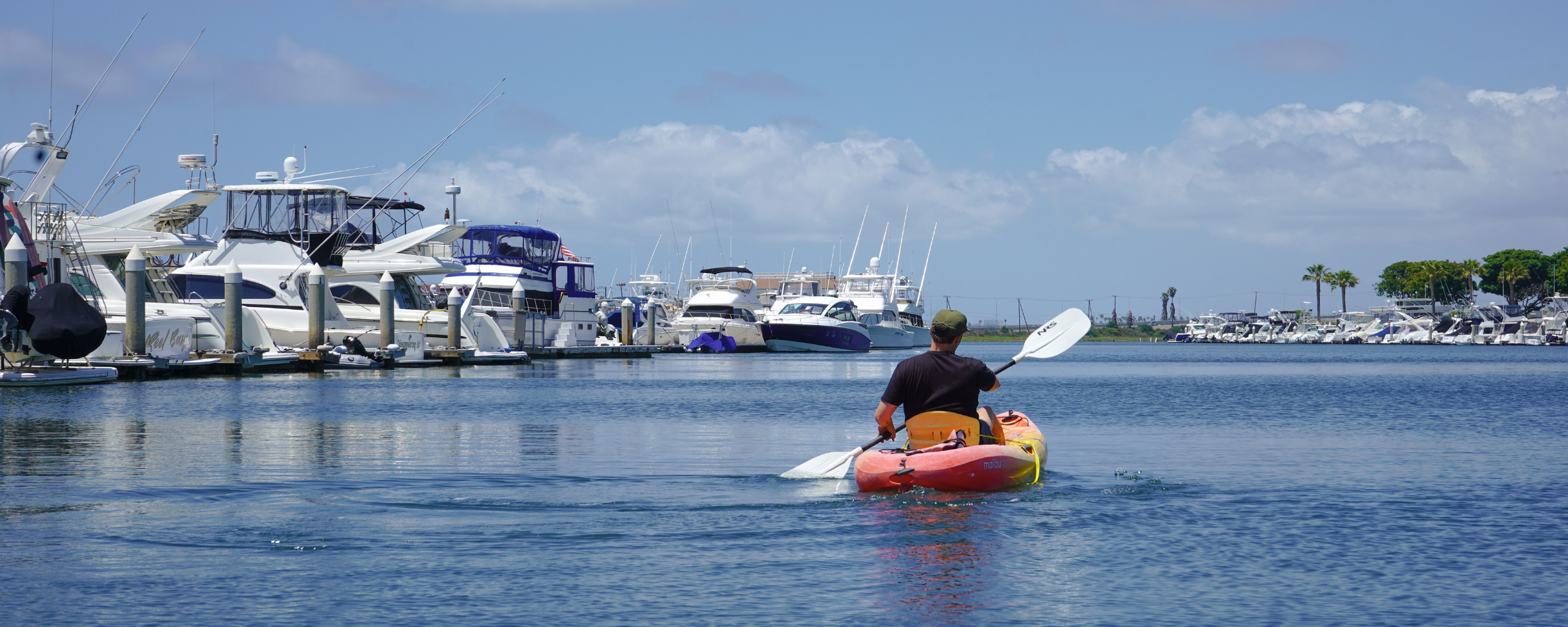 Person kayaking through Huntington Harbour near Huntington Beach in Sunset Beach, California. The waters of the canal in Huntington Harbour are calm.