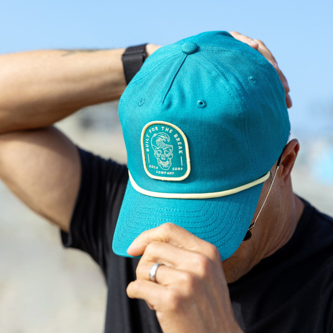 Person wearing a blue cap with a logo, outdoors on a clear day