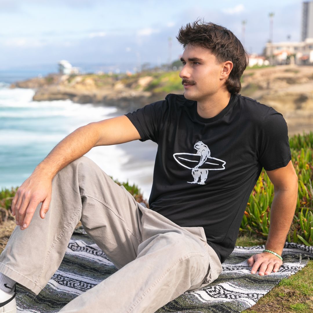 Simply Brutus Tee in Black from Everyday California. Casual fit, lightweight, breathable, and features Brutus the bear holding a surfboard.