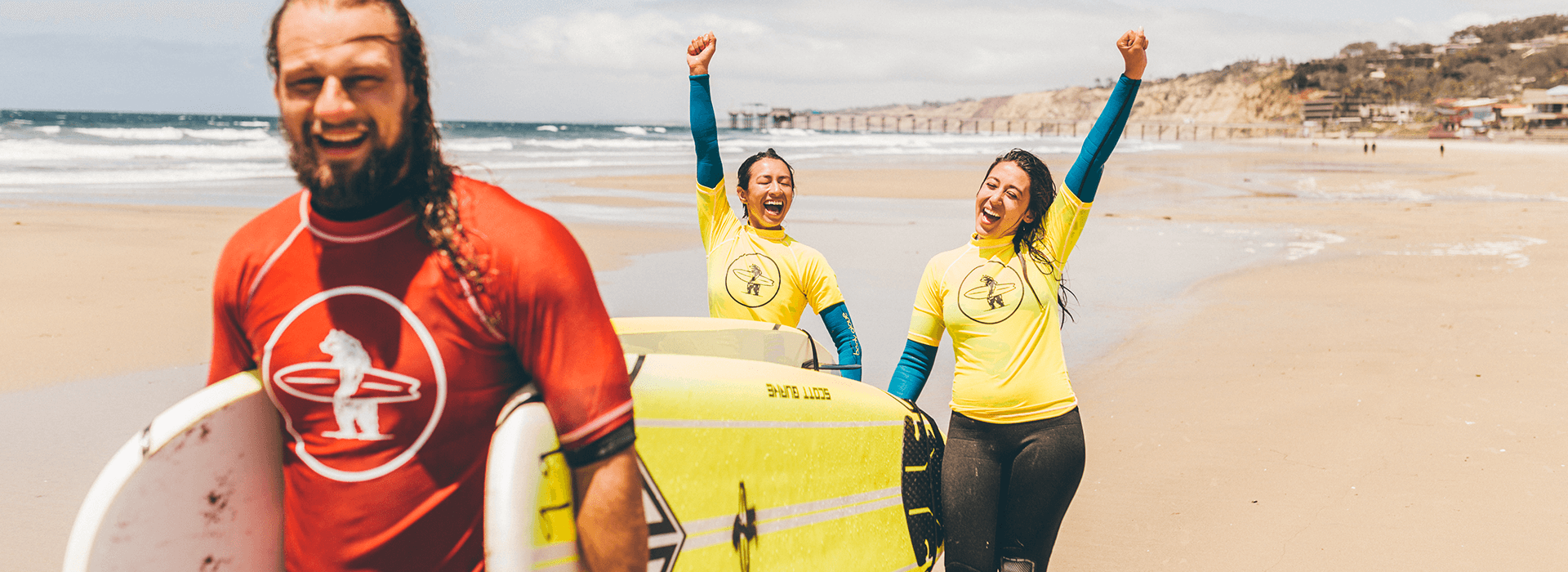 After a surf camp, two girls cheer with their instructor that they successfully caught some waves and stood up on the board in San Diego, La Jolla, California.