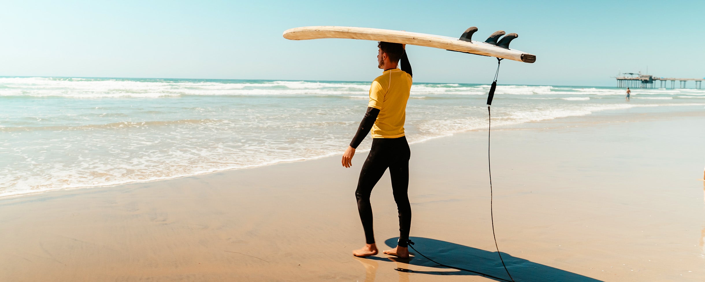 A surfboard rental tourist about to walk out into the ocean in La Jolla to catch some waves