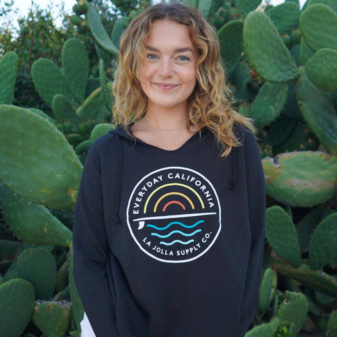 Baillee posing with EDCA sweater. Logo pictured with "Everyday California, La Jolla Supply co." written on it.