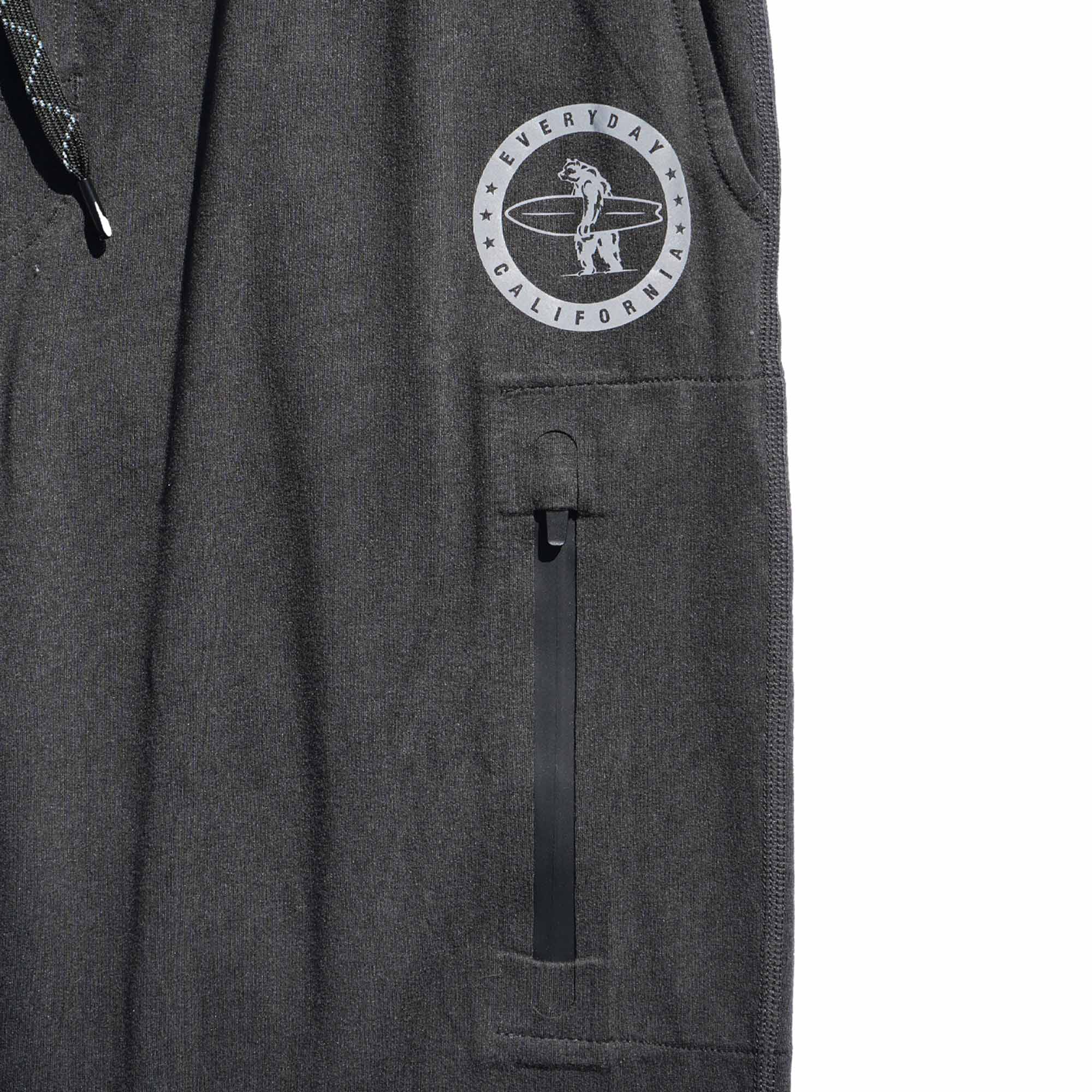 Black Bayside Performance joggers frontside image, featuring a small reflective vinyl logo of a bear holding a surfboard above the zip pocket on the thigh.