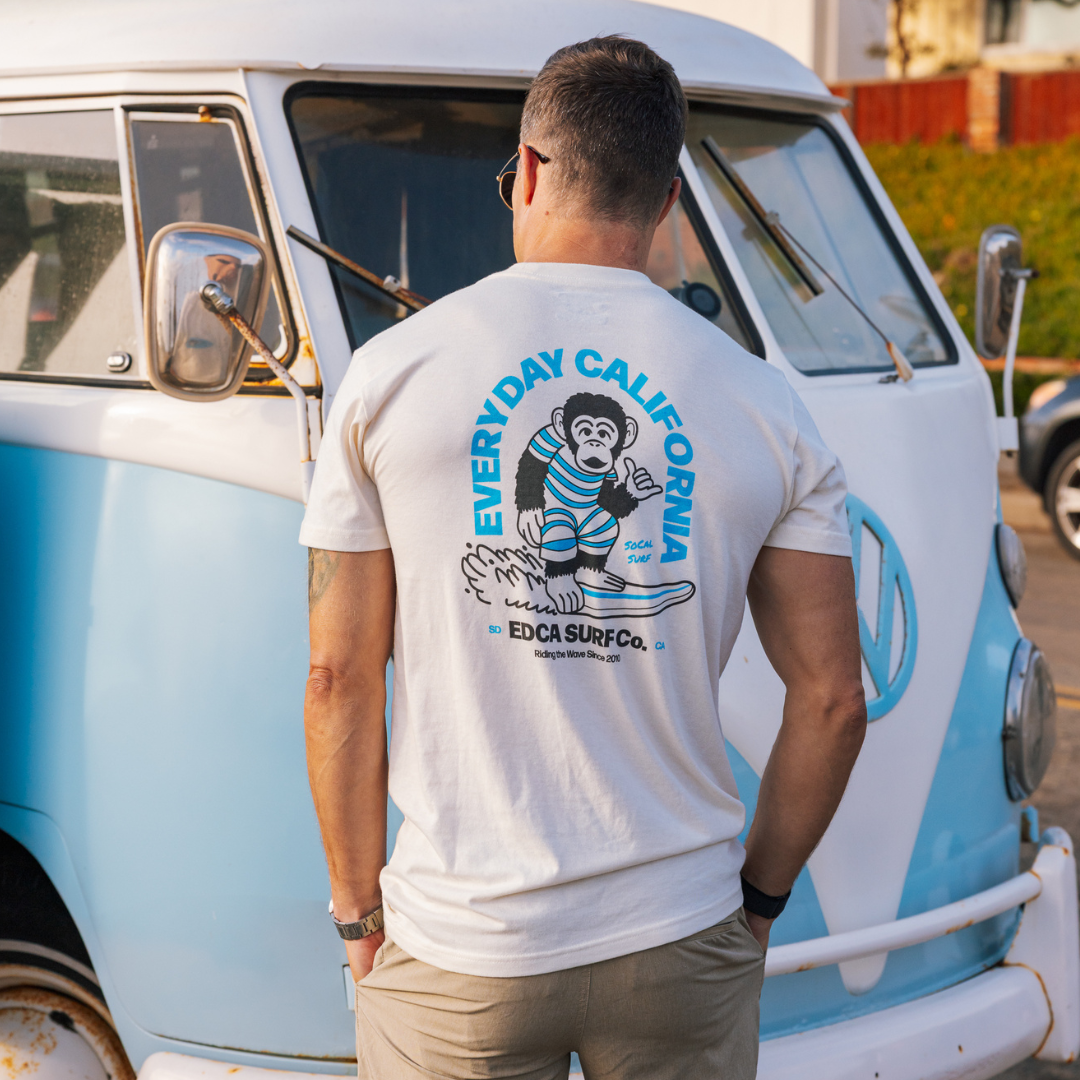 Man wearing a 'Everyday California' t-shirt standing next to a vintage van.