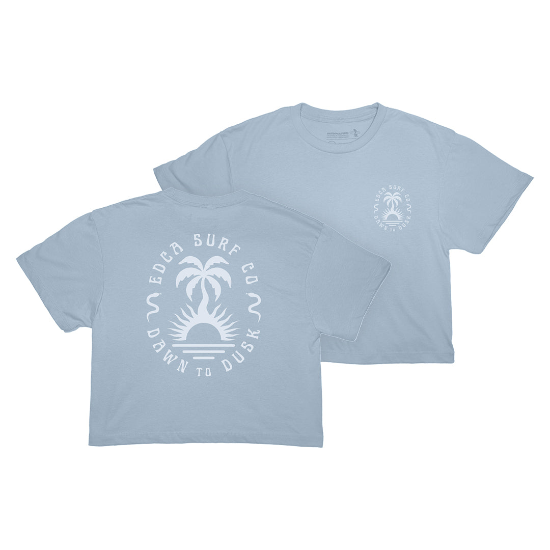 Light blue t-shirt with a palm tree and wave design on the upper left chest on the front of the tee, and center back on the back of the tee.