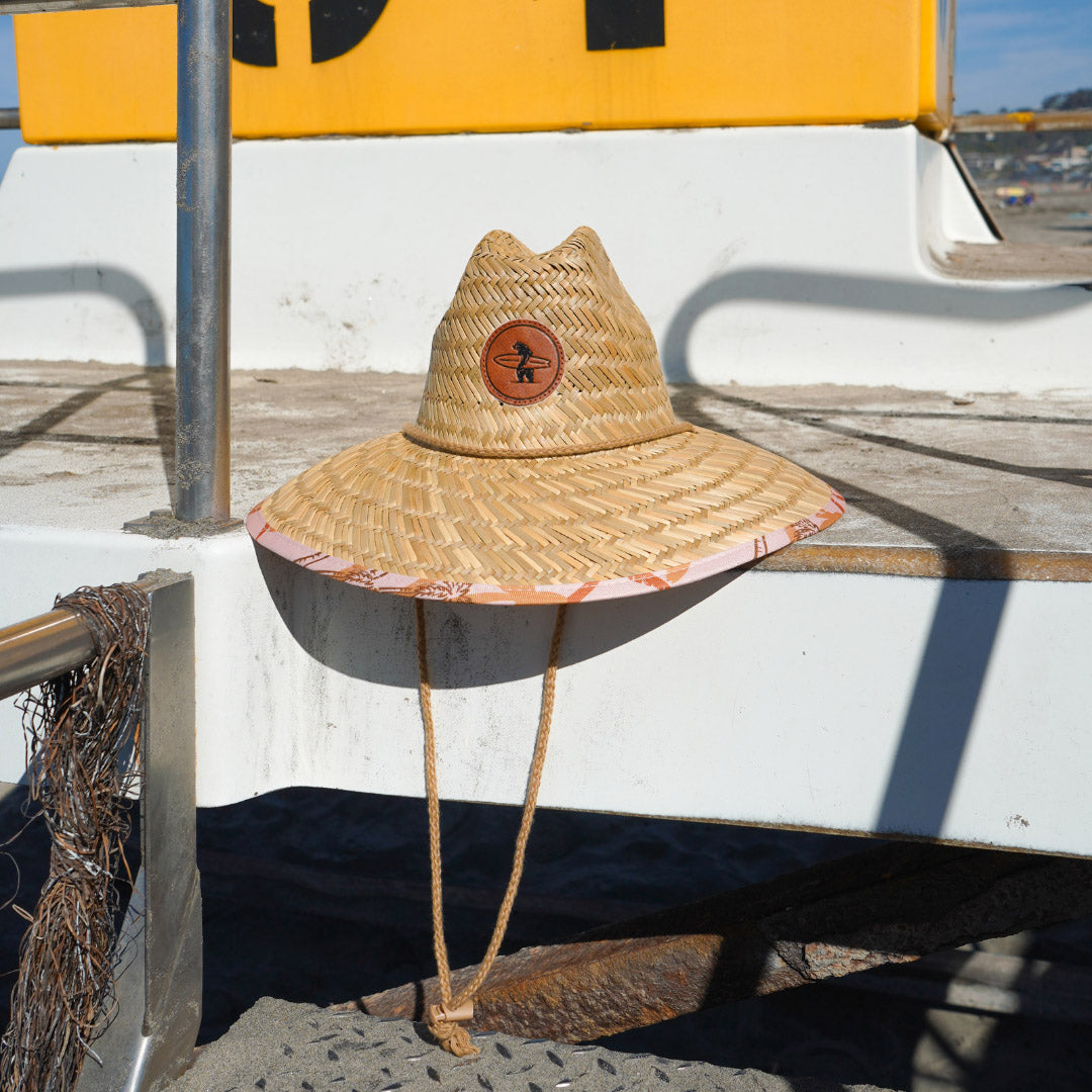 A beige Eddie Straw Hat with a wide brim and a logo patch on the crown, featuring a natural straw weave and an adjustable chin strap.