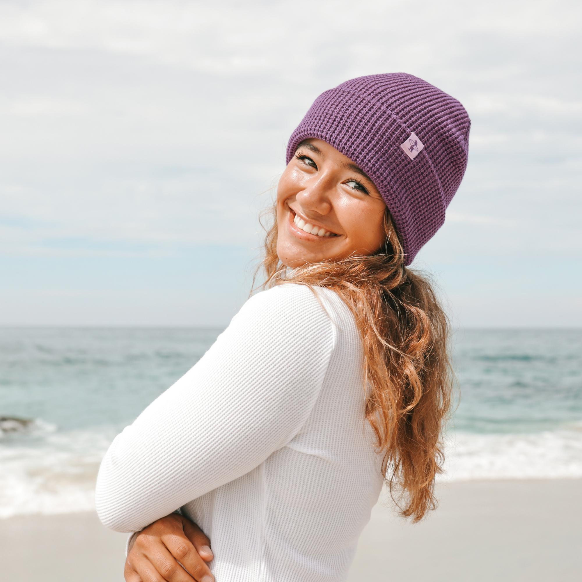 Woman wearing a purple knit hat on a beach