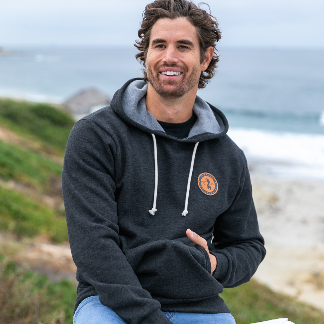 Male model wearing a charcoal grey Everyday California hoodie at the beach