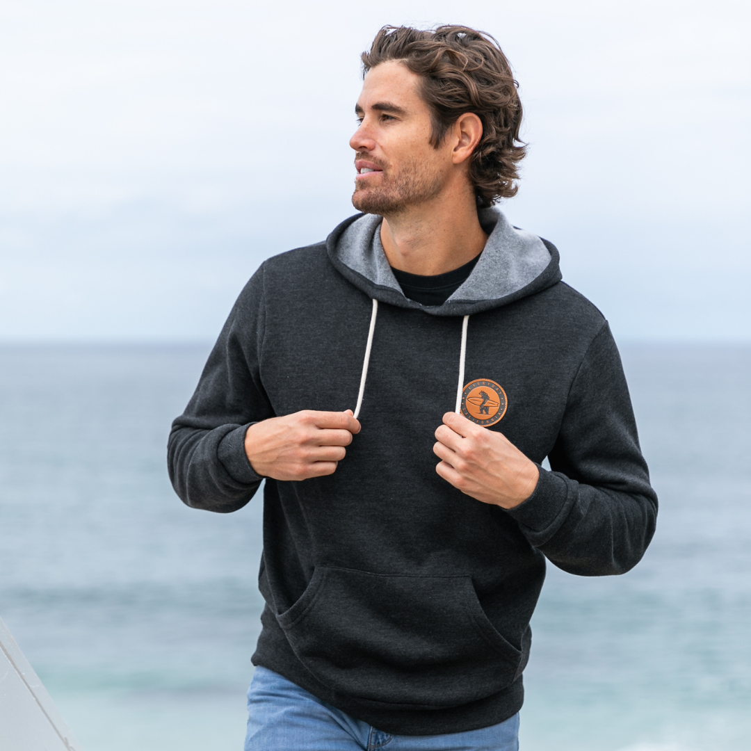 Male model wearing Everyday California hoodie with ocean view in the background