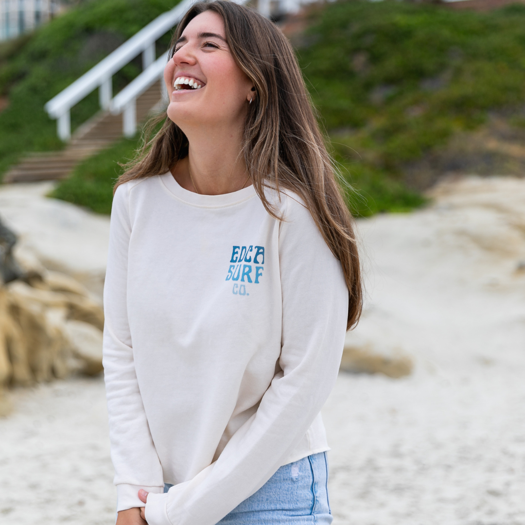 Female model wearing white Everyday California crewneck with the "EDCA Surf Co." logo on the upper right chest area