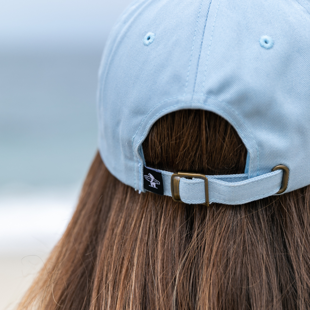 Closeup of the back of a light blue Everyday California brand hat worn by female model with brown hair
