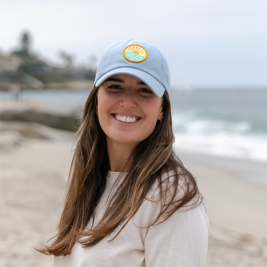 Headshot of a female model wearing light blue hat on the beach