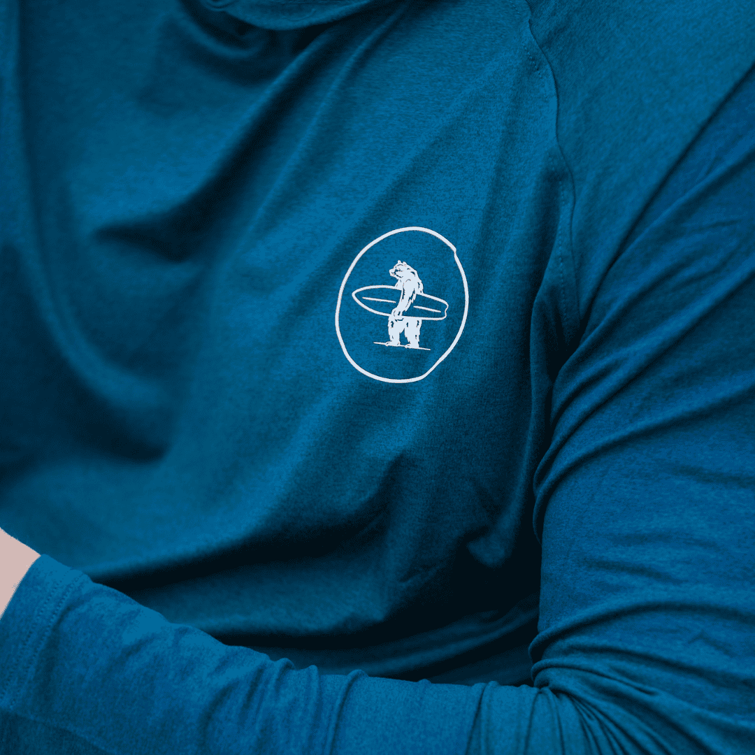 Closeup of blue Everyday California sweatshirt with white logo of bear holding surfboard