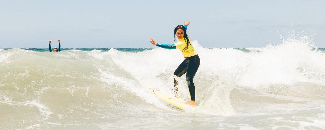 A private surf lesson in La Jolla with a women riding a wave on a surfboard.
