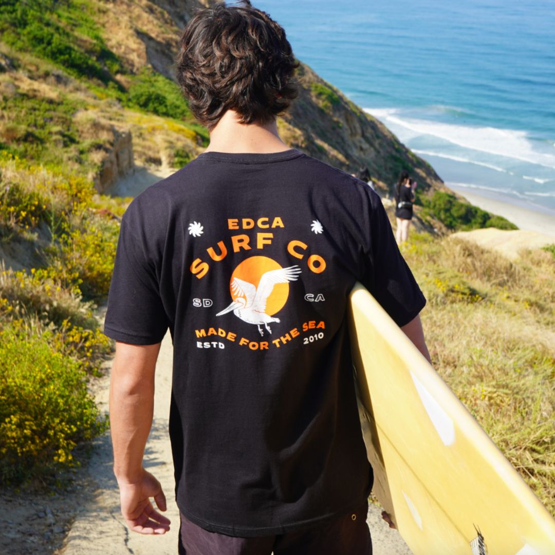 A California guy walking down to the beach with a surfboard