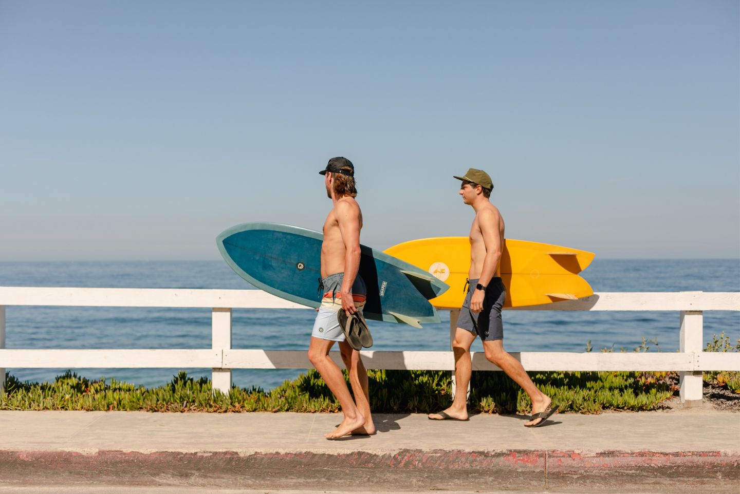 two guys walking on the coastline of San Diego wearing everyday California apparel 