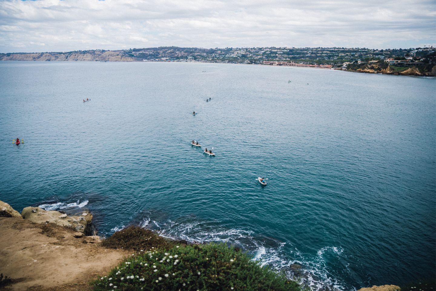 kayak tour from a bride eye view all in a line about to enter the sea caves on the La Jolla coast 