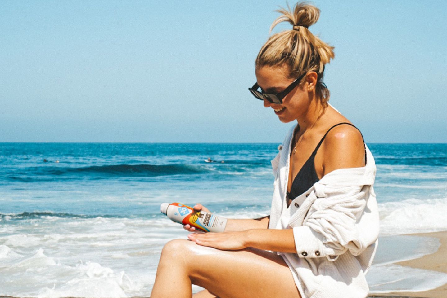 A girl on the beach holding Everyday California's Reed Safe Sunscreen mineral based 