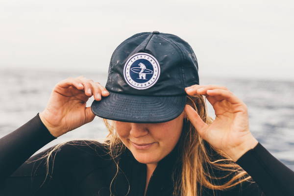 a girl wearing a floating waterproof hat in front of the ocean 