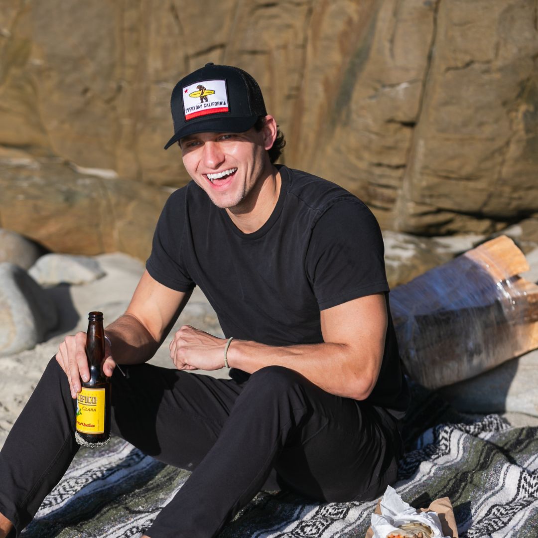 Man laughing on the beach in his black Shores Hat from Everyday California 