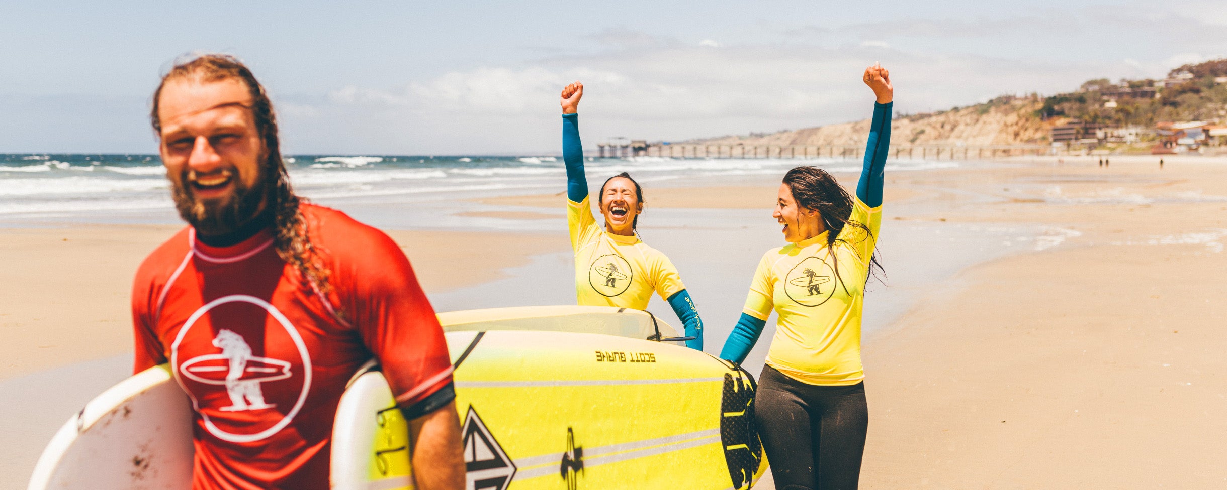 After a private surf lesson, two girls cheer with their instructor that they successfully caught some waves and stood up on the board in San Diego, La Jolla, California. 