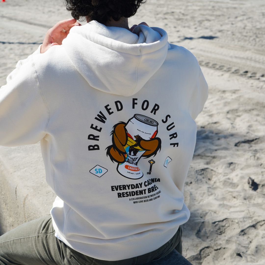 Man on the beach in San Diego wearing the everyday California Coastal Ale hoodie 