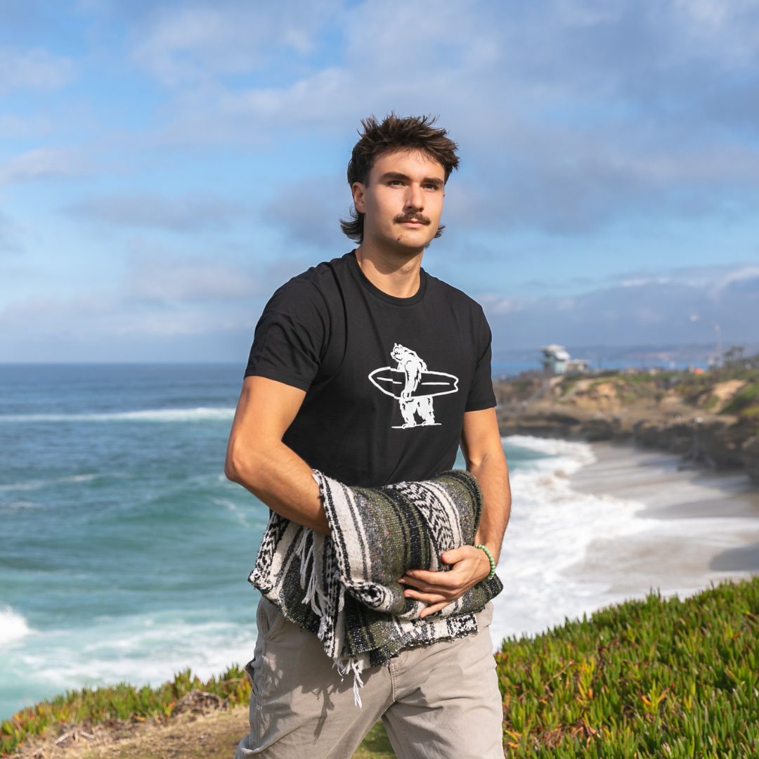 Simply Brutus Tee in Black from Everyday California. Casual fit, lightweight, breathable, and features Brutus the bear holding a surfboard.