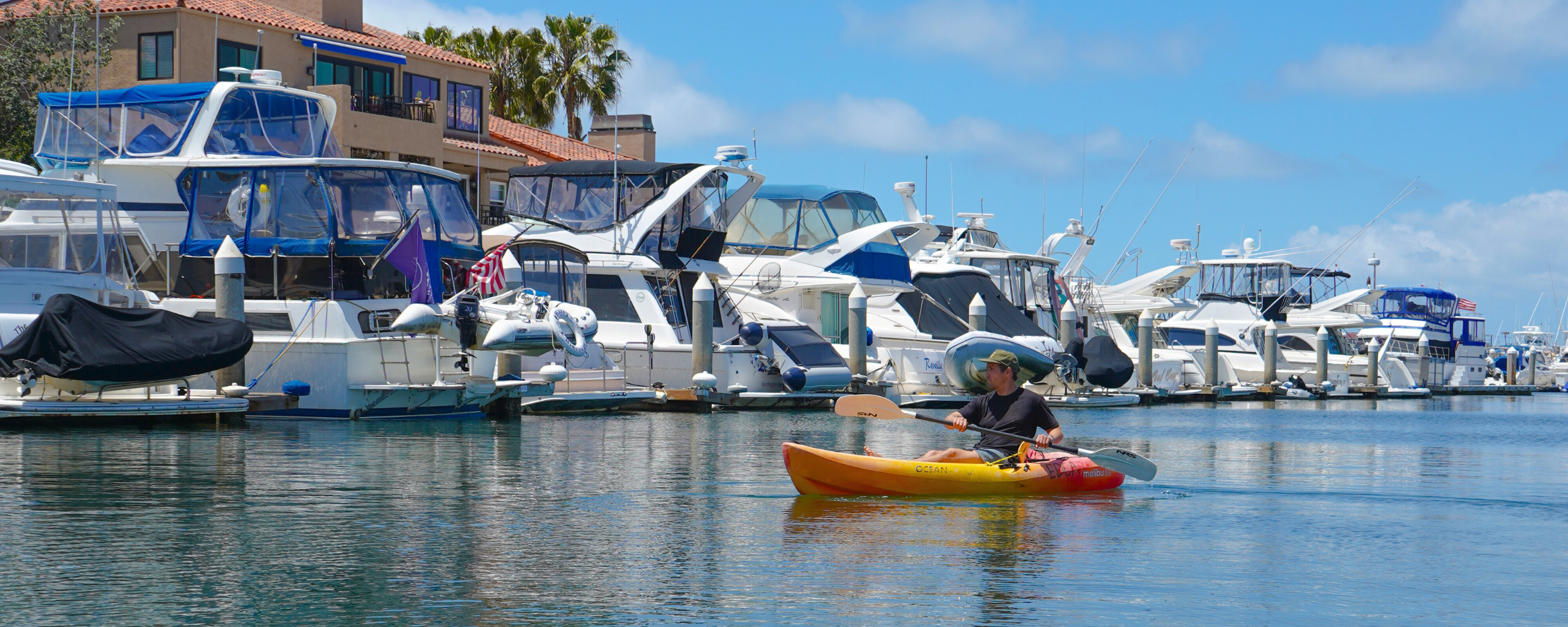 Kayaker paddling through the calm waters of the canals in Huntington Harbour near Huntington Beach, California. 
