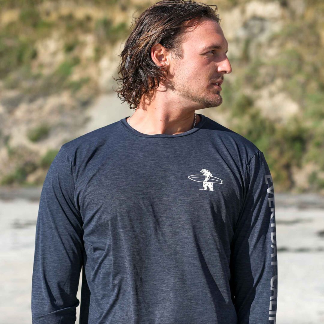 A man wearing an Everyday California rash guard in Charcoal on the beach in the sun