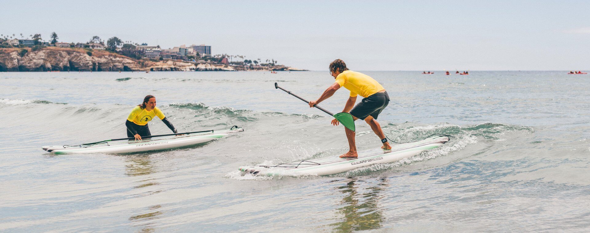 SUP Lesson with Everyday California catching a small wave on their paddle board