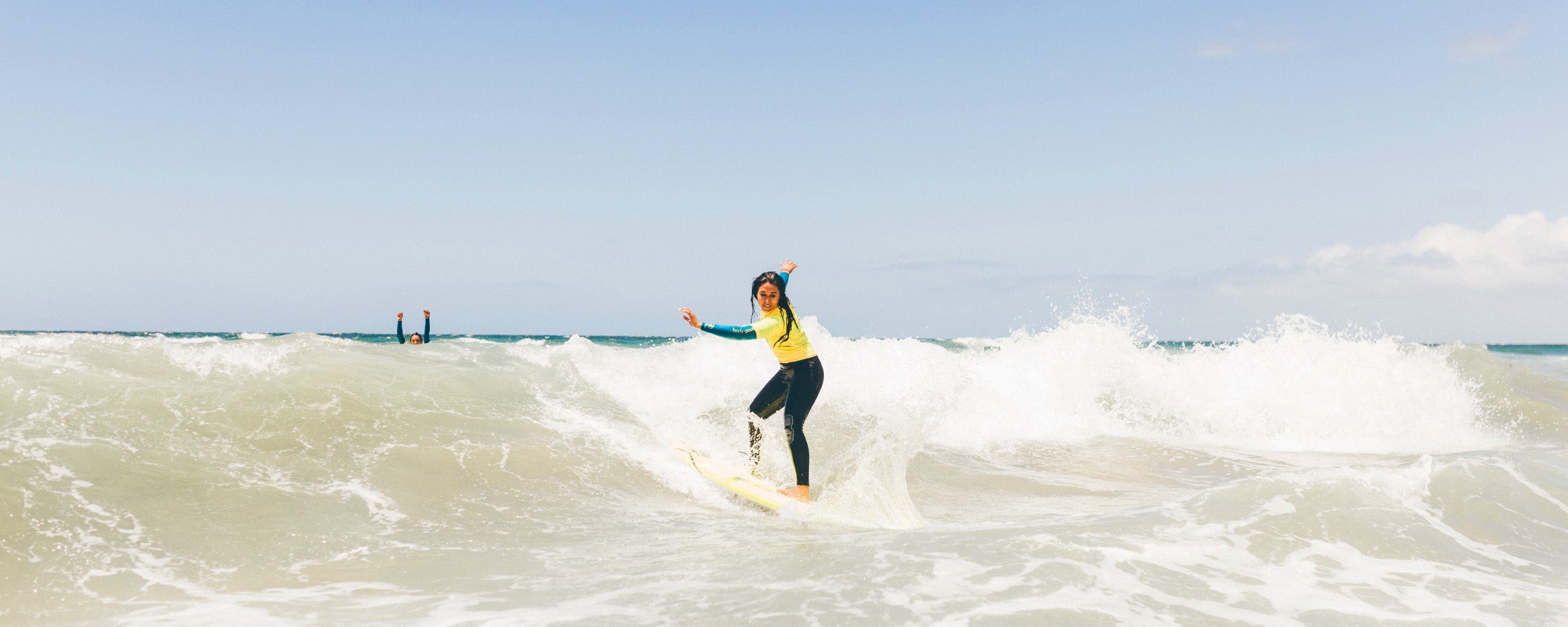 A girl catching a wave on a private surf lesson in San Diego California with Everyday California. 