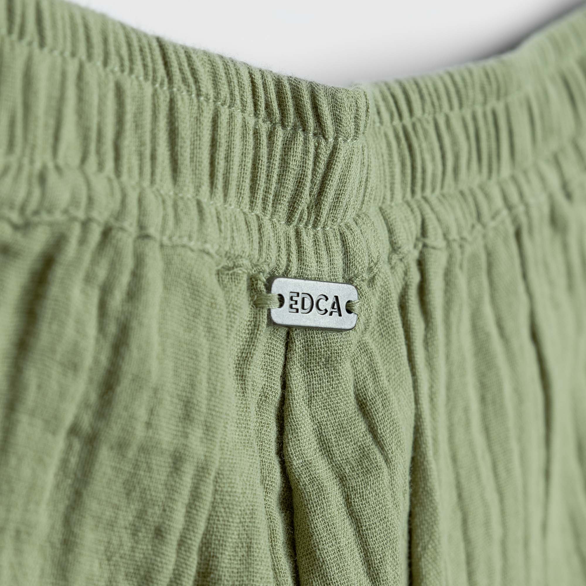 Close-up of green fabric with a visible brand tag on a white background