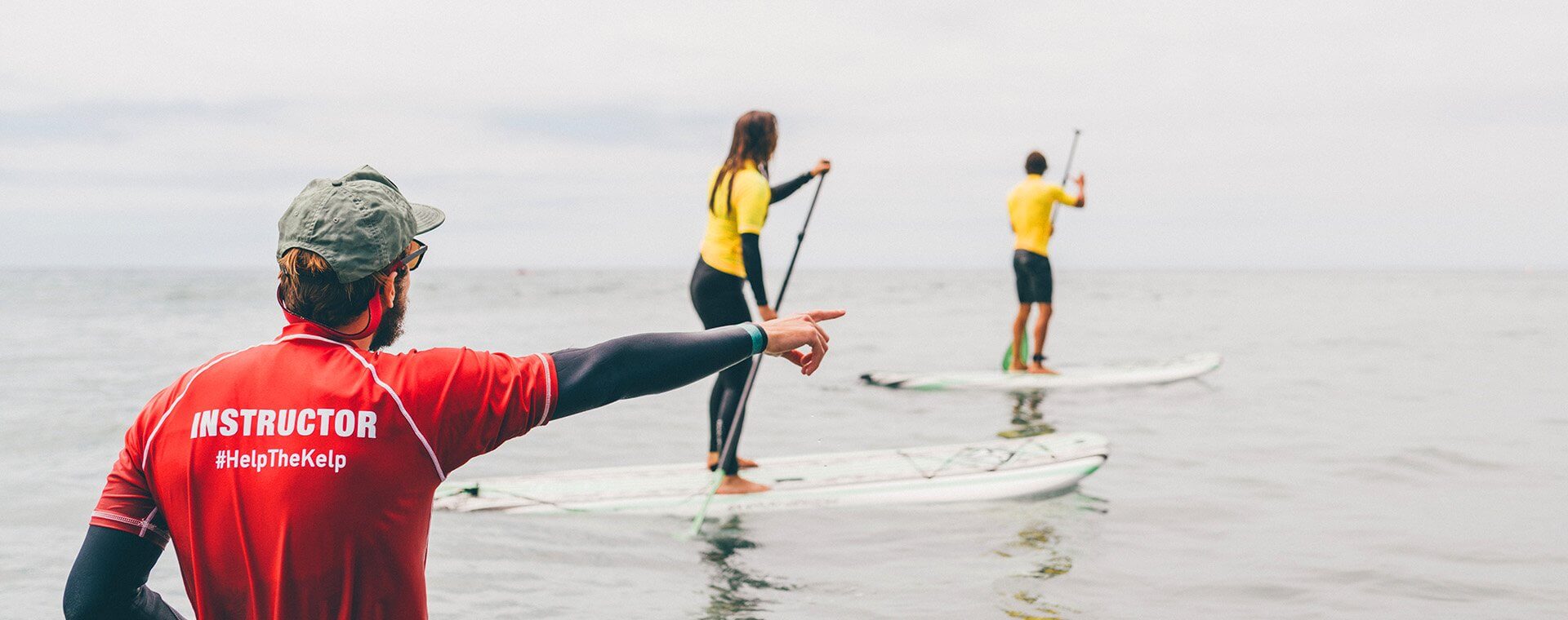 Lessons - SUP Lessons with Everyday California in La Jolla, California. Two people on their paddle boards in the water getting instructions on how to paddle on their Stand Up Paddle Board. With their instructor from Everyday California 