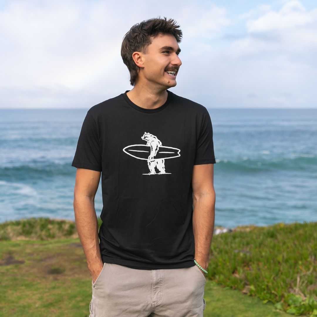 Simply Brutus Tee in Black from Everyday California. Casual fit, lightweight, breathable, and features Brutus the bear holding a surfboard.