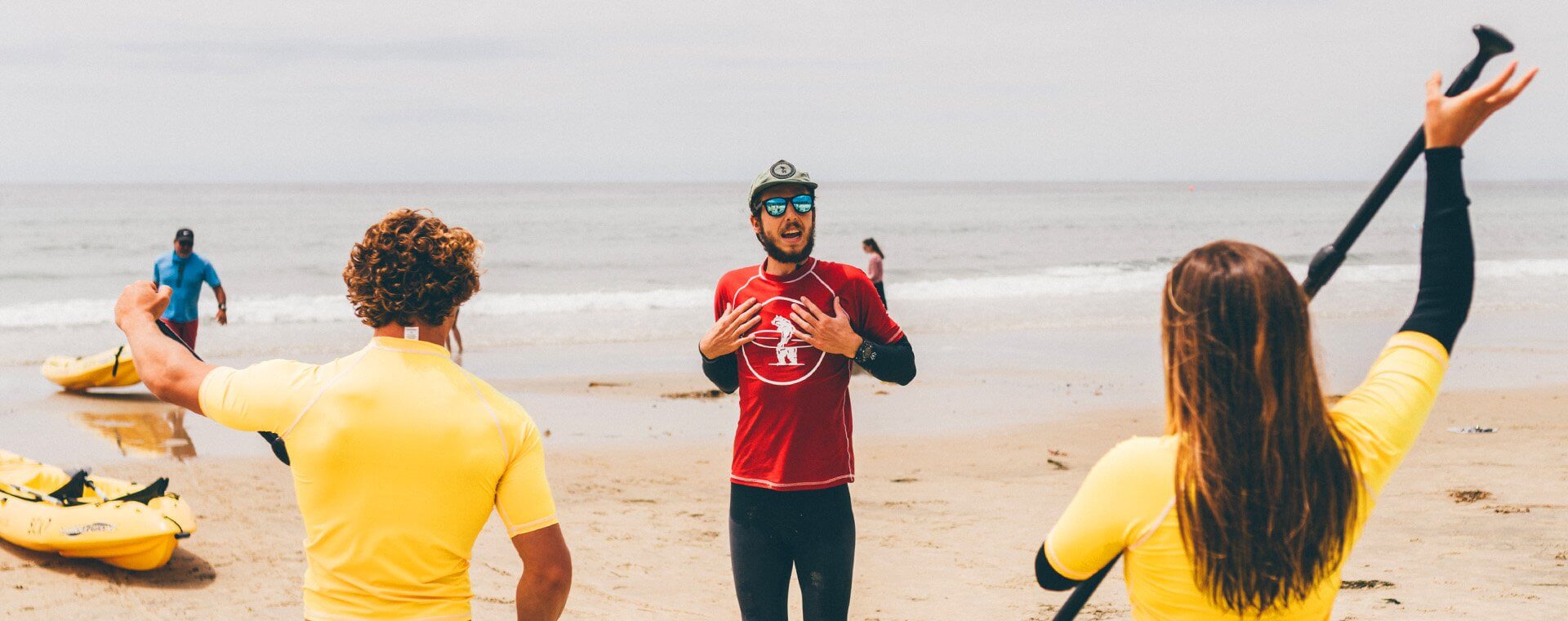 SUP Group Lesson in San Diego, La Jolla, California. Instructor from Everyday California is telling his guests how to stand up on their board and how to paddle on the ocean during the Stand Up Paddle Board Lesson. 