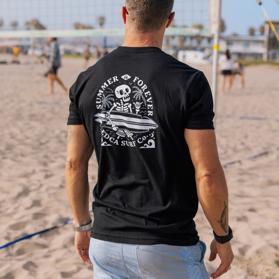 Man wearing a black t-shirt with a skull graphic design with Summer Is Forever on the beach