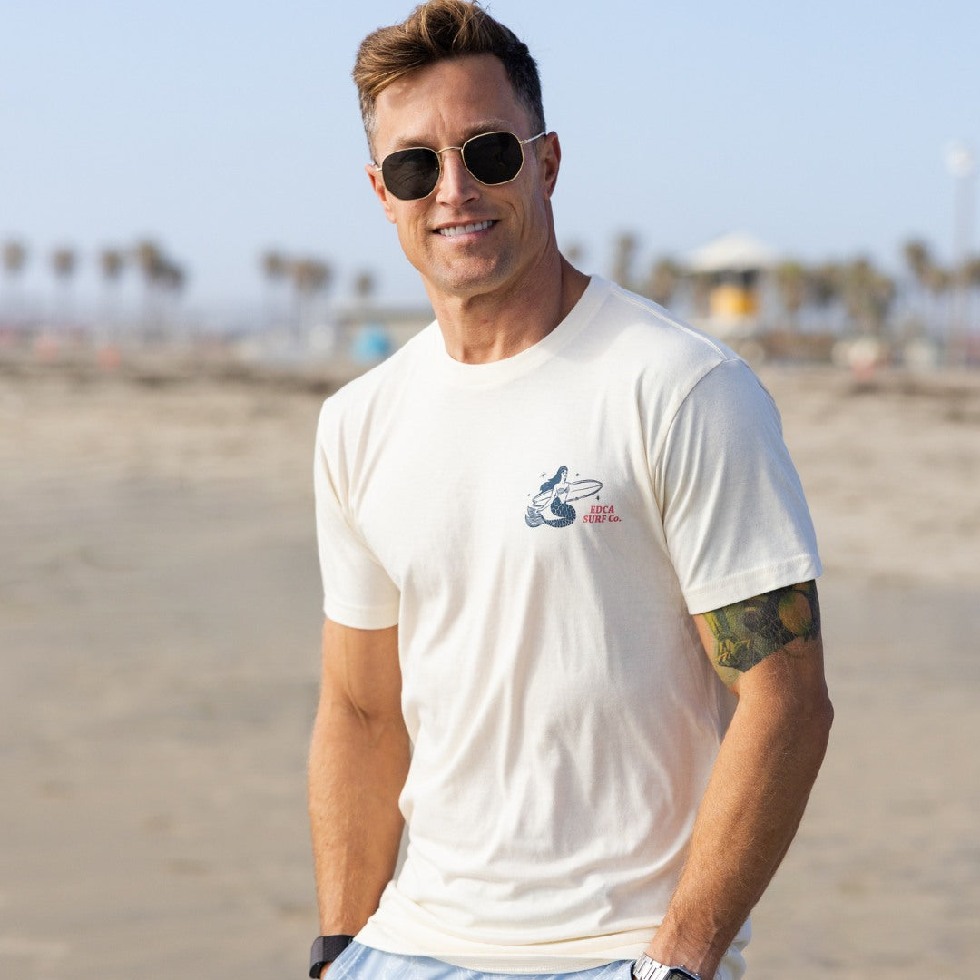 Man wearing a white t-shirt with a logo on a beach