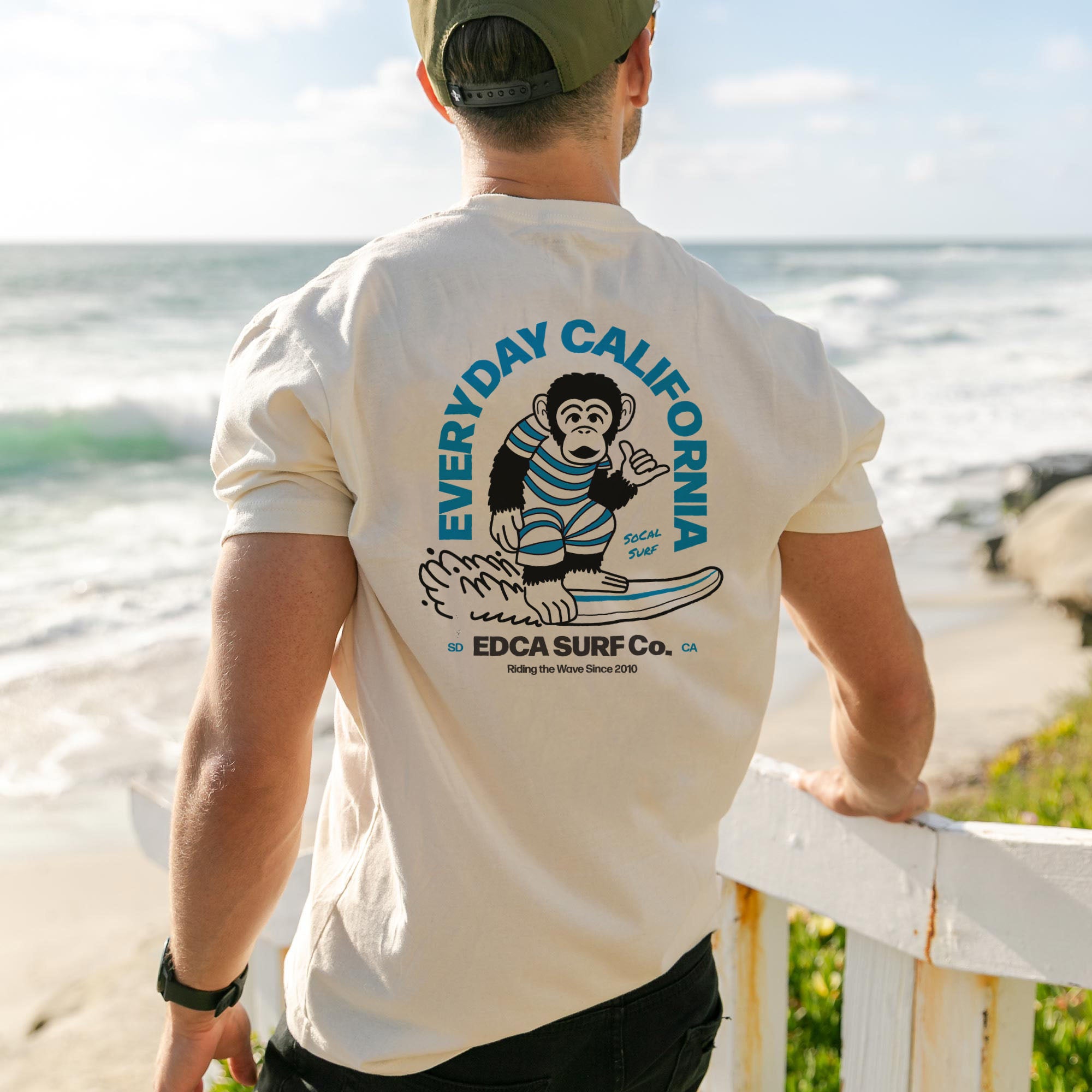A man looking out onto the water at the beach wearing the Everyday California chango tee. 