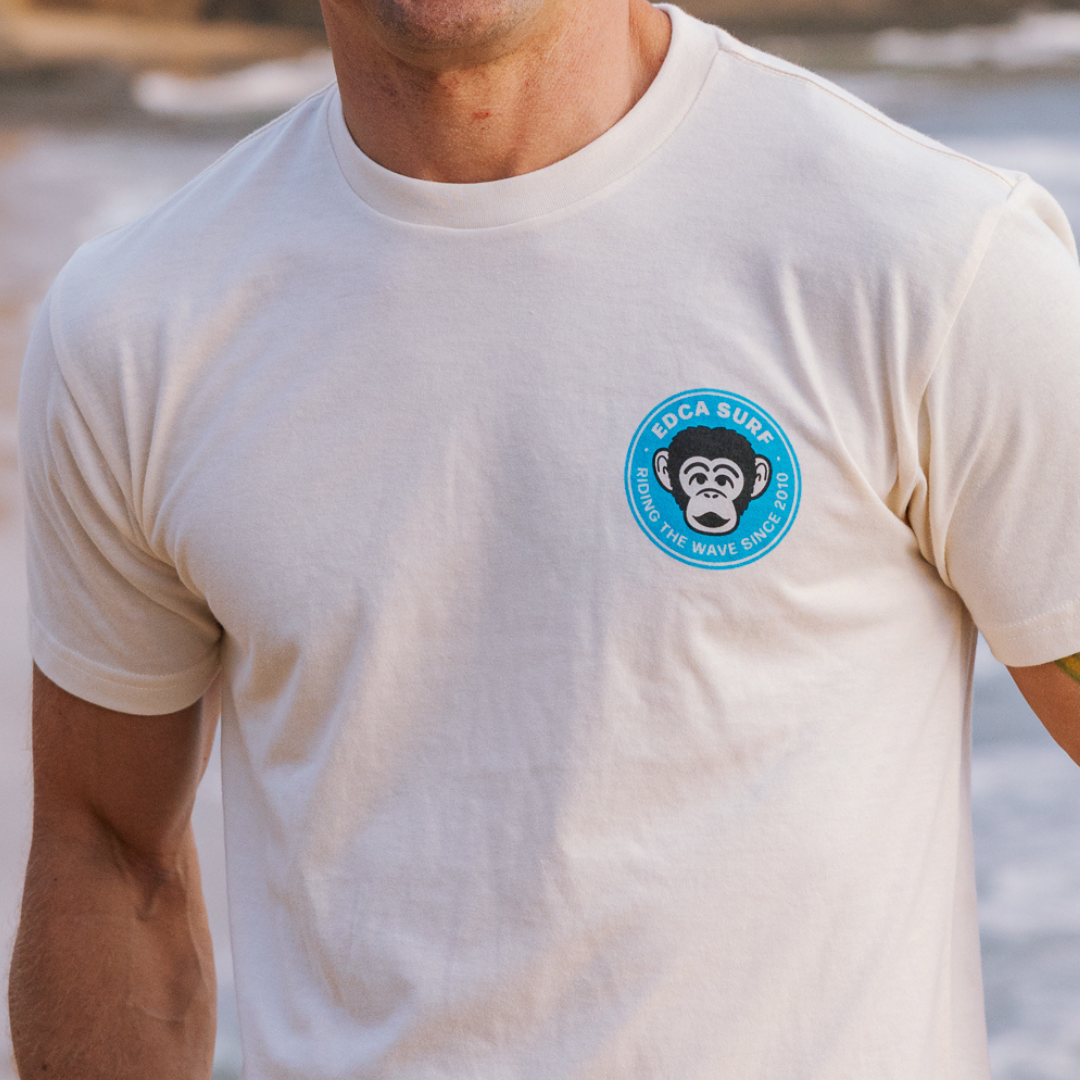 Person wearing a white t-shirt with a blue logo on a beach