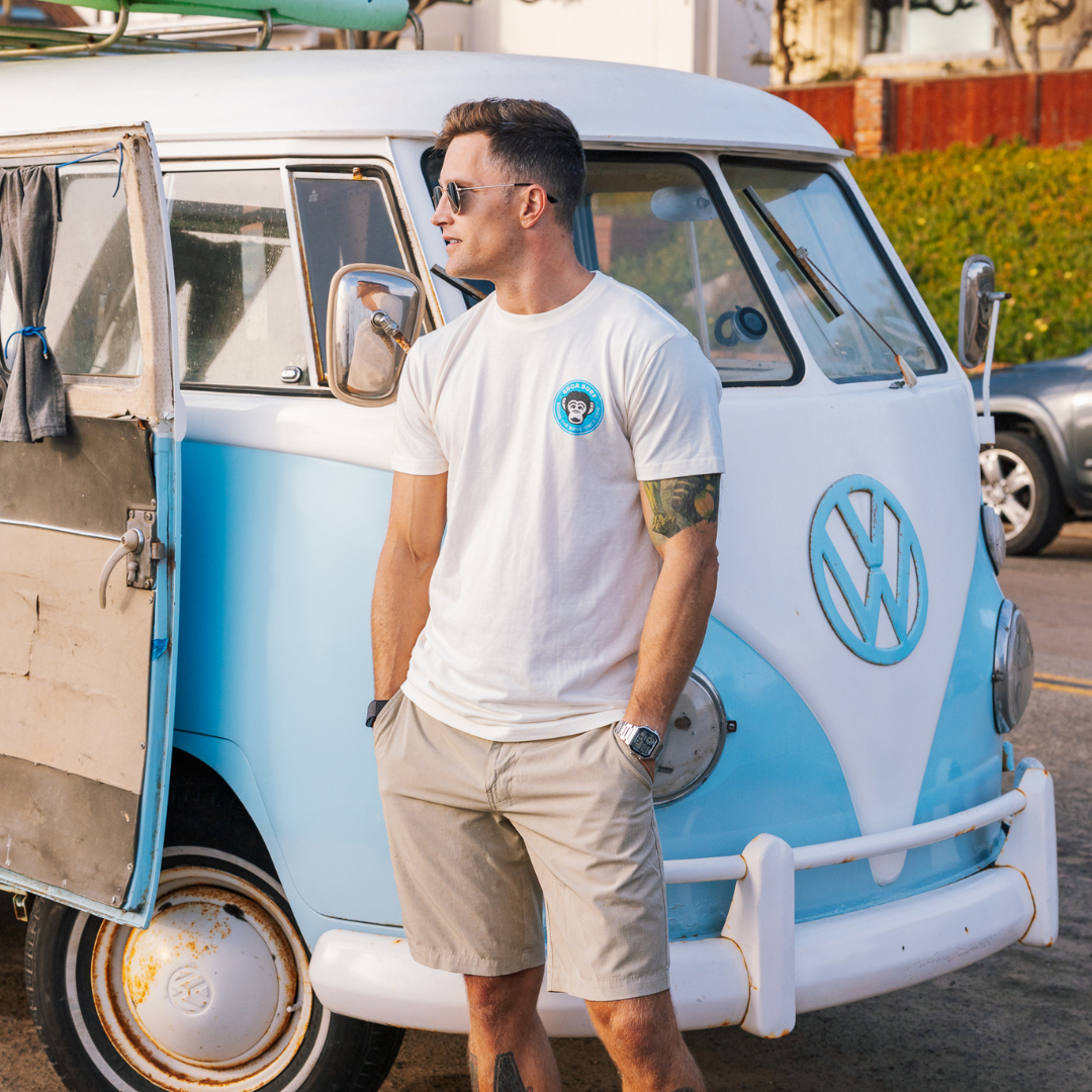 Man standing next to a vintage Volkswagen van with a blue and white color scheme.