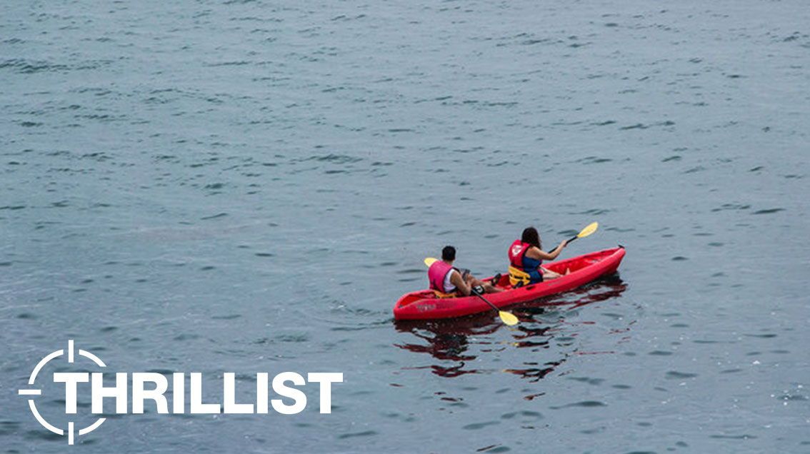 Photo of two people on one red kayak in the ocean in La Jolla.