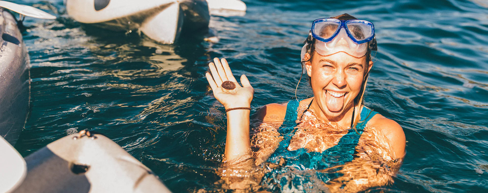 Photo of a girl holding a sand dollar in her hand in the ocean and smiling