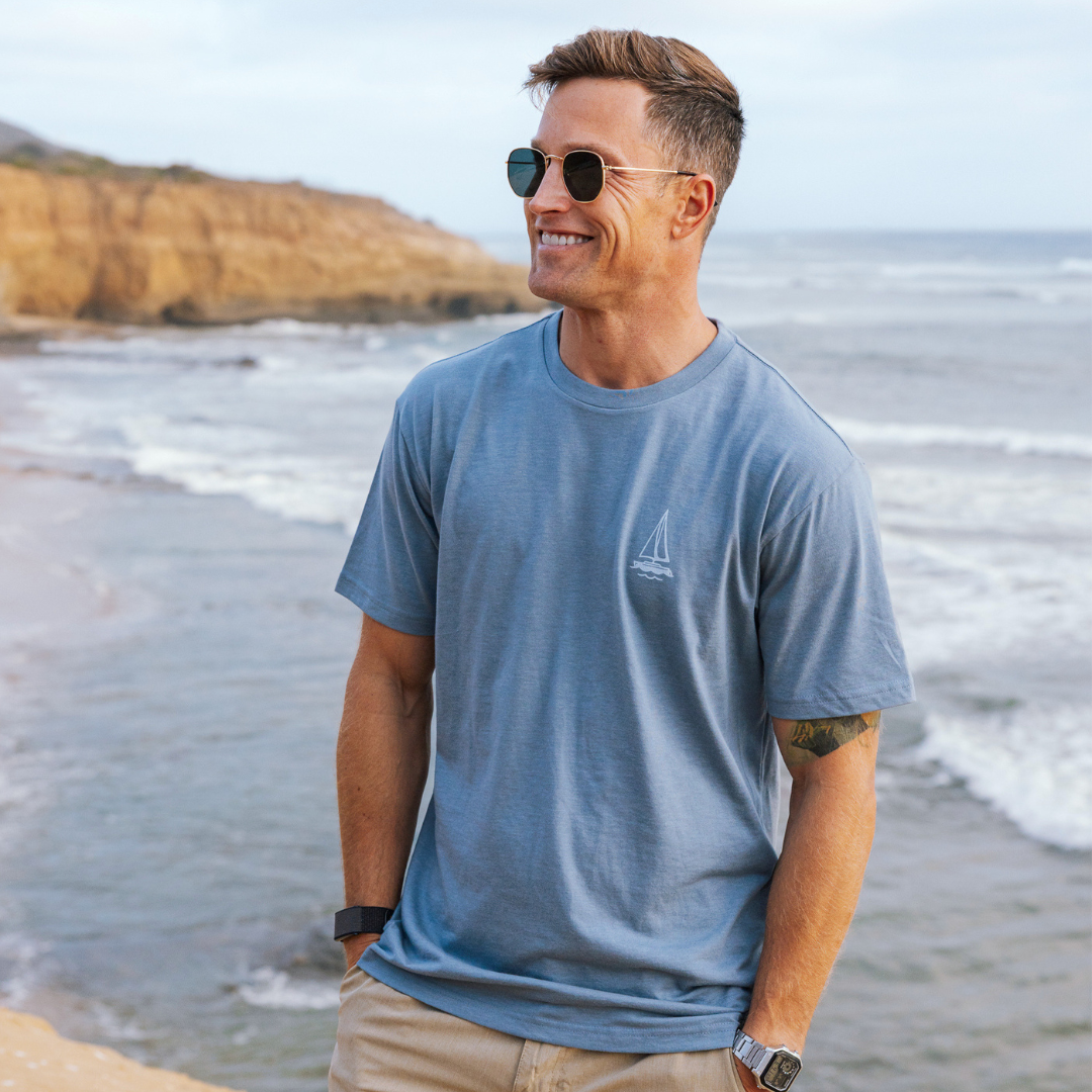 Man wearing a blue t-shirt with a logo on a beach